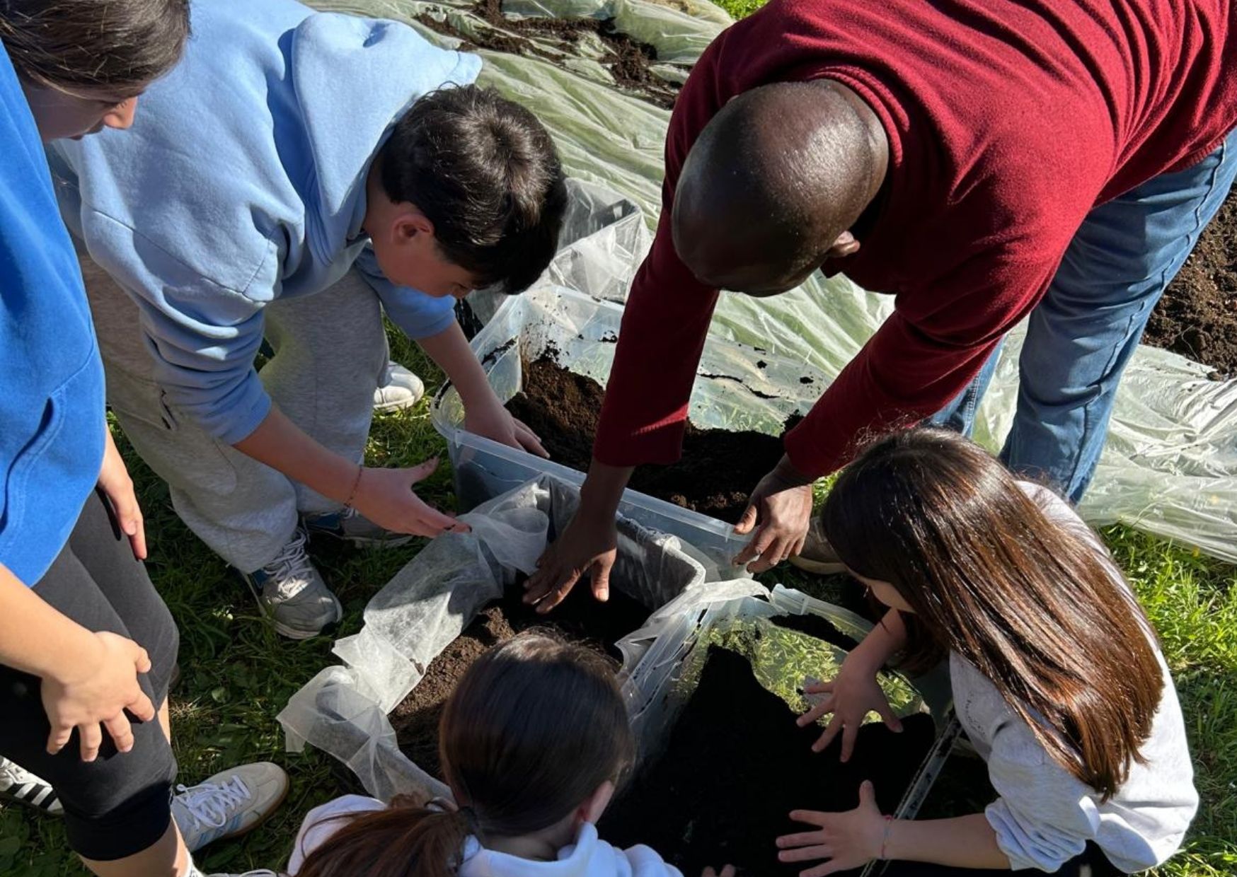 Modibo che mette la terra nella cassetta con i bambini